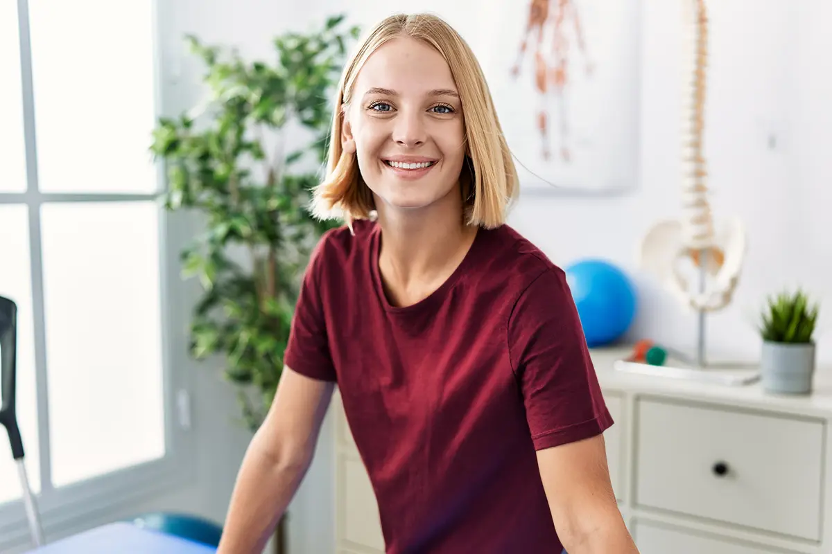 Freundliche Physiotherapeutin in moderner Praxisumgebung, bereit für die nächste Behandlung.