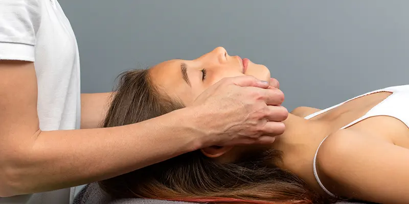 Physiotherapeutin behandelt die Kiefermuskulatur einer Patientin bei einer CMD-Therapie zur Linderung von Beschwerden.