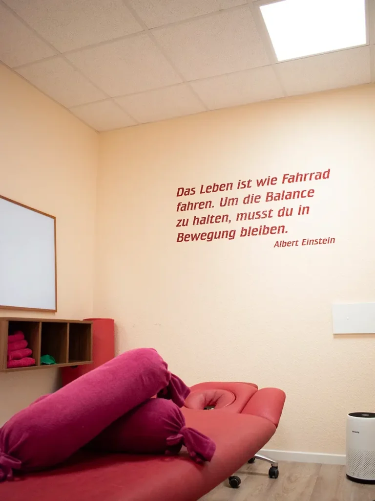 Behandlungsraum in der Physiotherapie-Praxis Celle mit Zitat von Albert Einstein an der Wand und roter Liege.