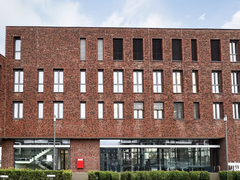 Außenansicht des Gebäudes der Physiotherapie Mobili Misburg mit roter Backsteinfassade und modernen Fenstern.