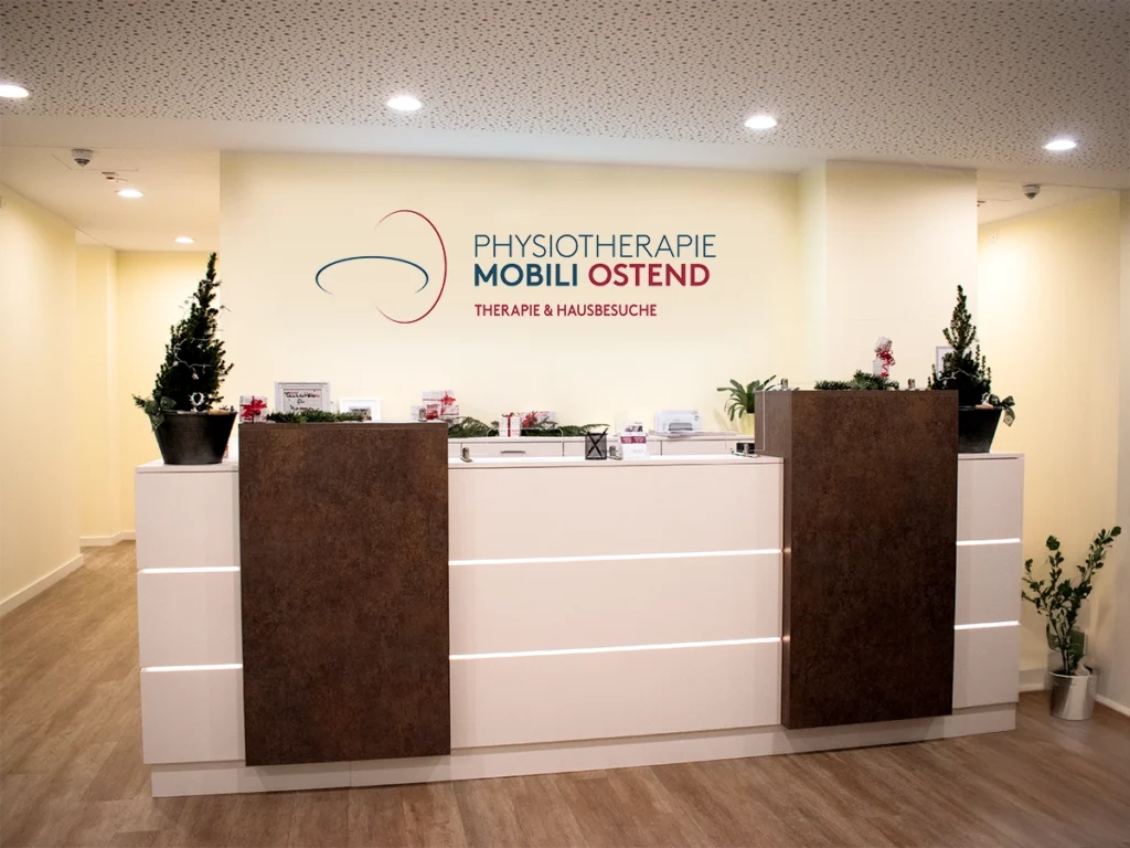 Empfangsbereich der Physiotherapie Mobili Ostend mit moderner weiß-brauner Rezeption.
