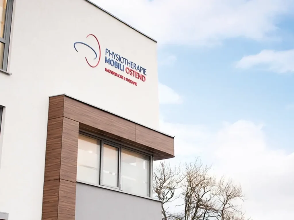 Fassade der Physiotherapie Mobili Ostend in Hildesheim mit Logo und moderner Architektur unter blauem Himmel.