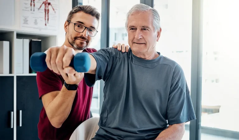 Therapeut unterstützt älteren Mann beim Krafttraining zur neurologischen Rehabilitation.
